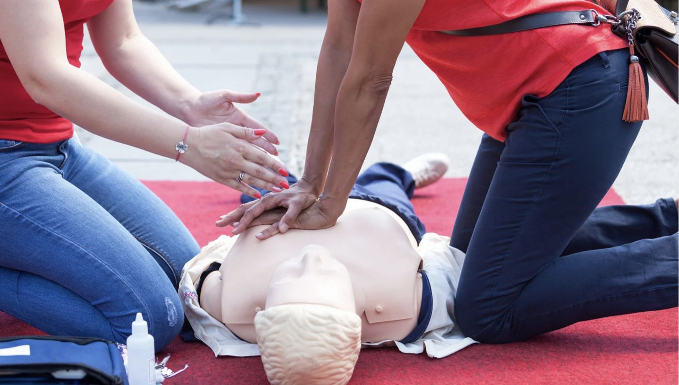 Students practicing chest compressions on a CPR manikin with an instructor
